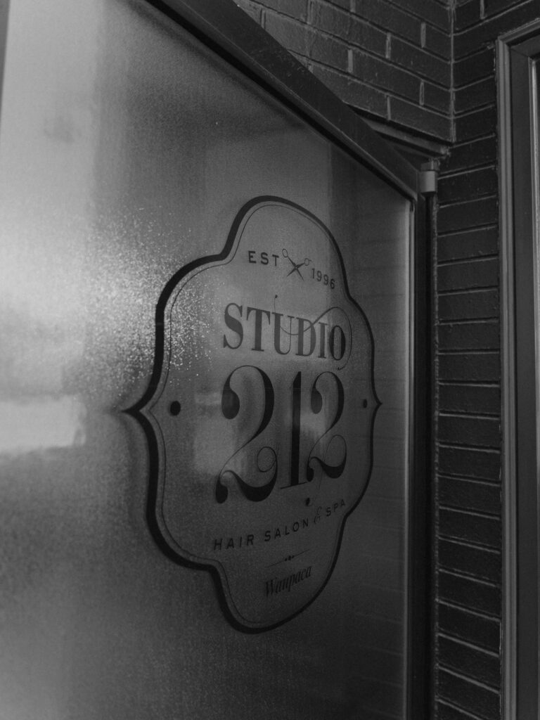 - Ibi David Salon in Westlake, OH Frosted glass door with a sign that reads “Studio 212 Hair Salon & Spa, Est. 1996, Waupaca” in black lettering. - Ibi David Salon in Westlake, OH